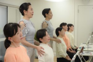 生徒様の肩に手を添えて、姿勢を確認している小林かおる